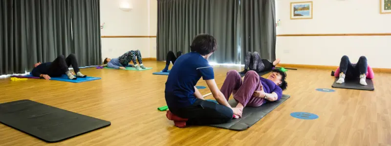 Instructor providing hands-on correction during a specialised Pilates class in Corfe Mullen, Dorset