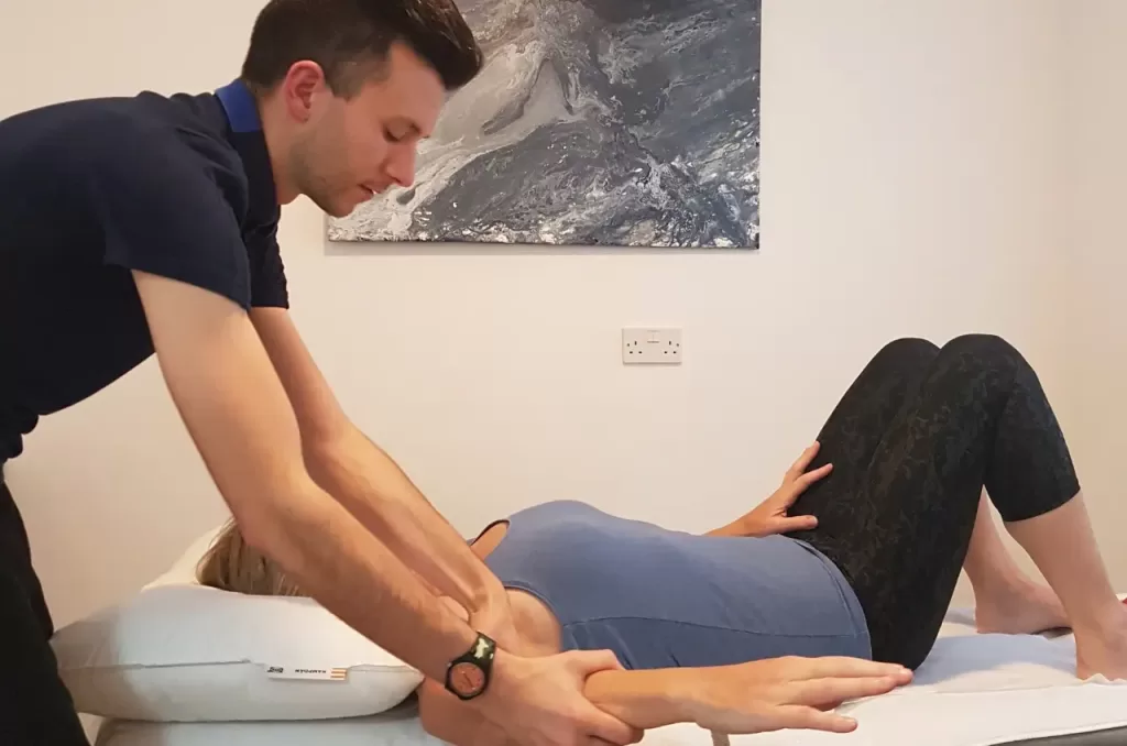 Sports massage therapist performing pain relief treatment for a client’s arm during a movement therapy session in Dorset