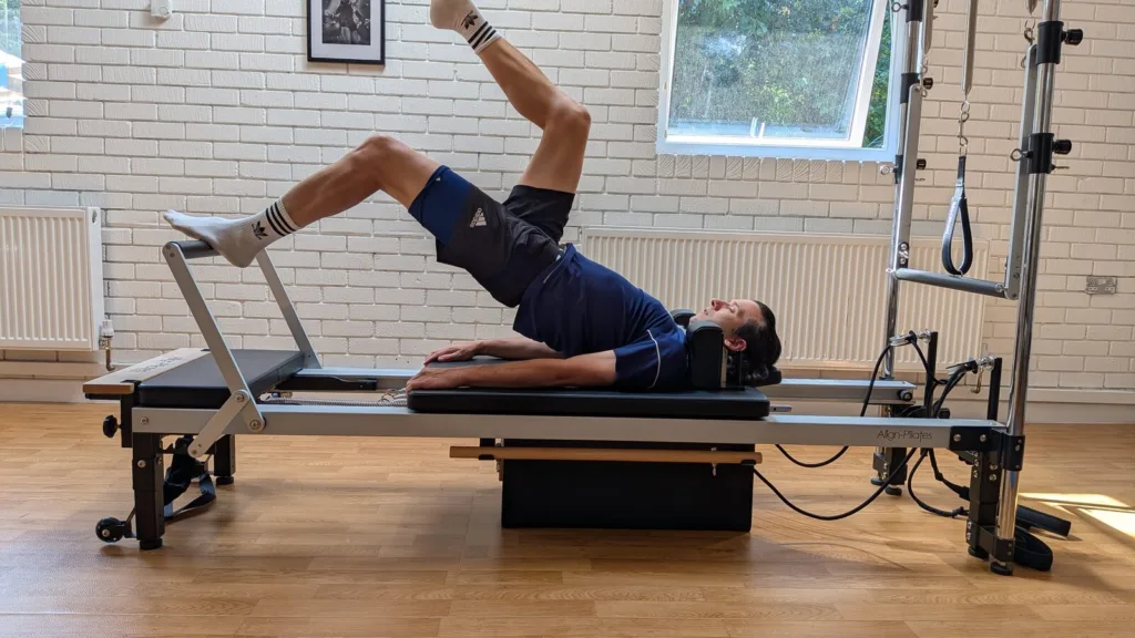 Client performing a one-legged bridge on the Reformer, a progressive hamstring loading exercise in Broadstone