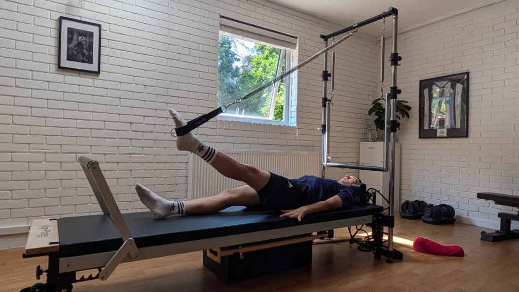 Client performing a straight leg push-down on the Reformer for hamstring tendinopathy rehab in Broadstone